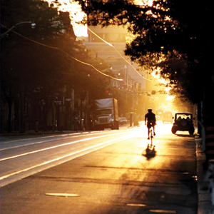 Photograph of a road cyclist with the rising sun at his back