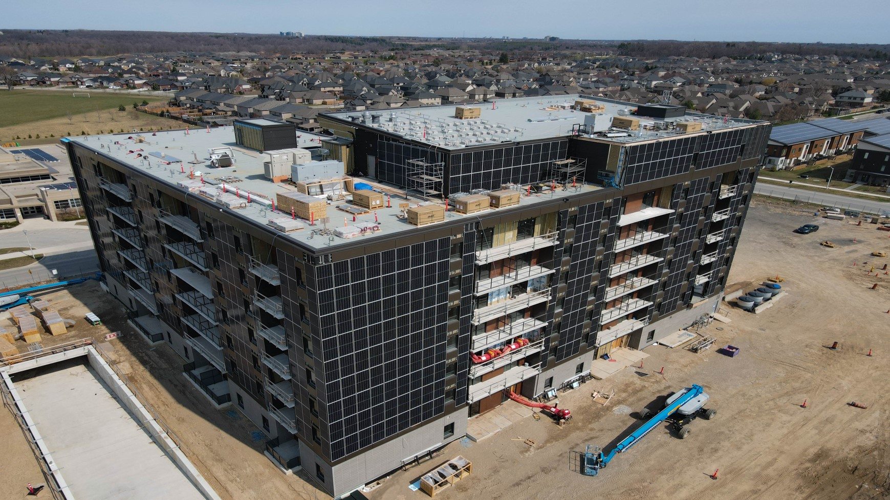 An aerial photograph of a parking garage with solar PV installed on the building façade. Additionally, more than 120kW of PV will be added to the roof during the Summer of 2021. The adjacent Building 16 will soon be constructed with similar PV capacity.