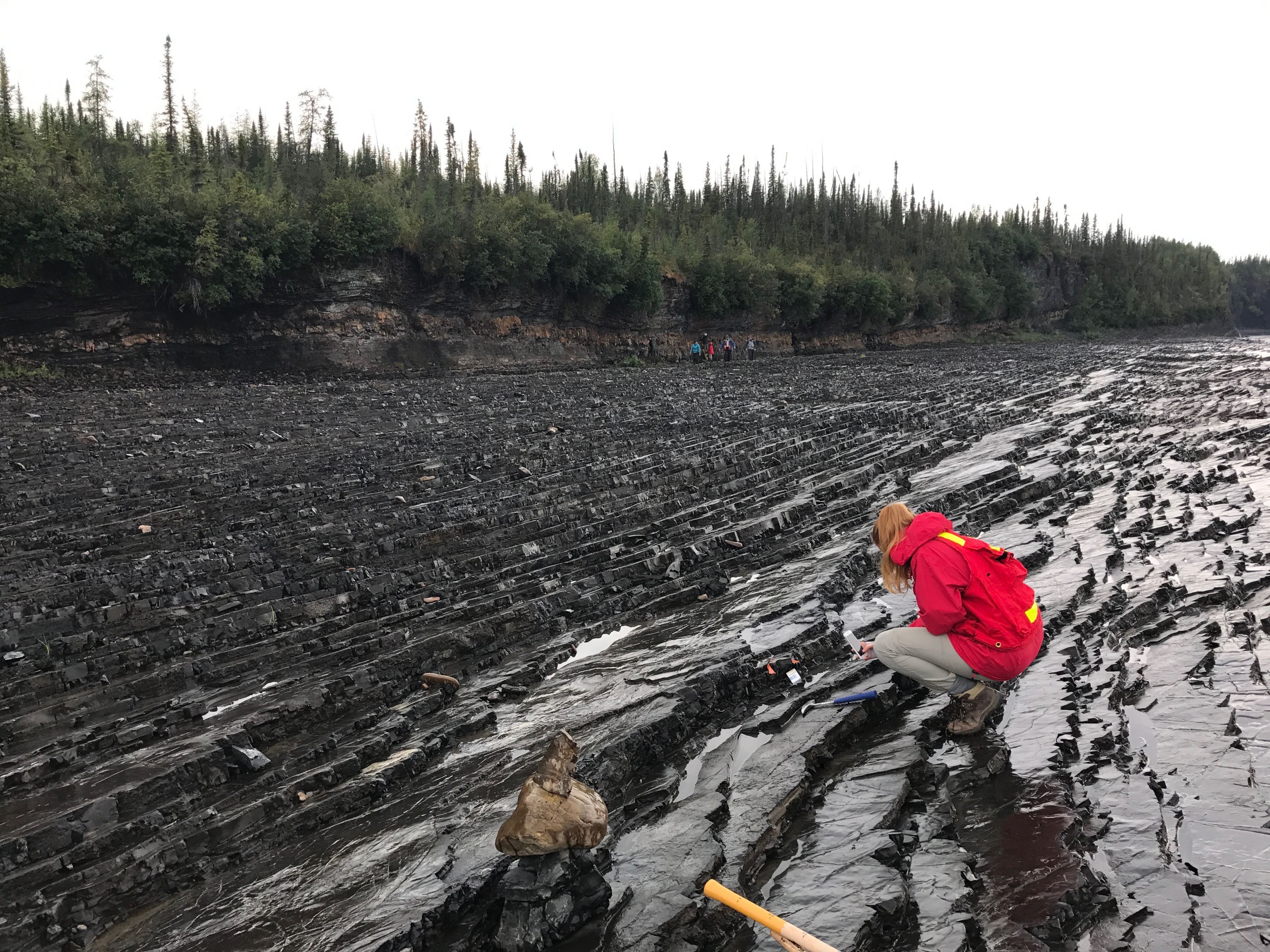 A researcher studies black shales on the Peel River in central Yukon. These shales can contain nickel, zinc, molybdenum, and gold.