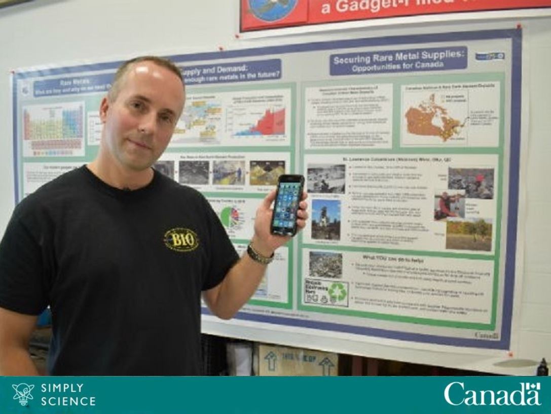 NRCan reseach scientist Michael Parsons stands in front of a poster board with a cell phone in his left hand