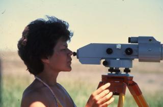 Technician looking through an automatic level on a tripod in a field