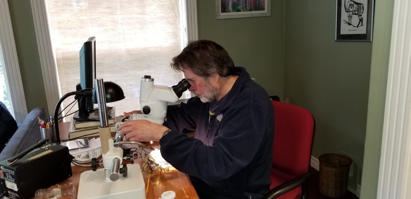 A man examines a specimen under a microscope 